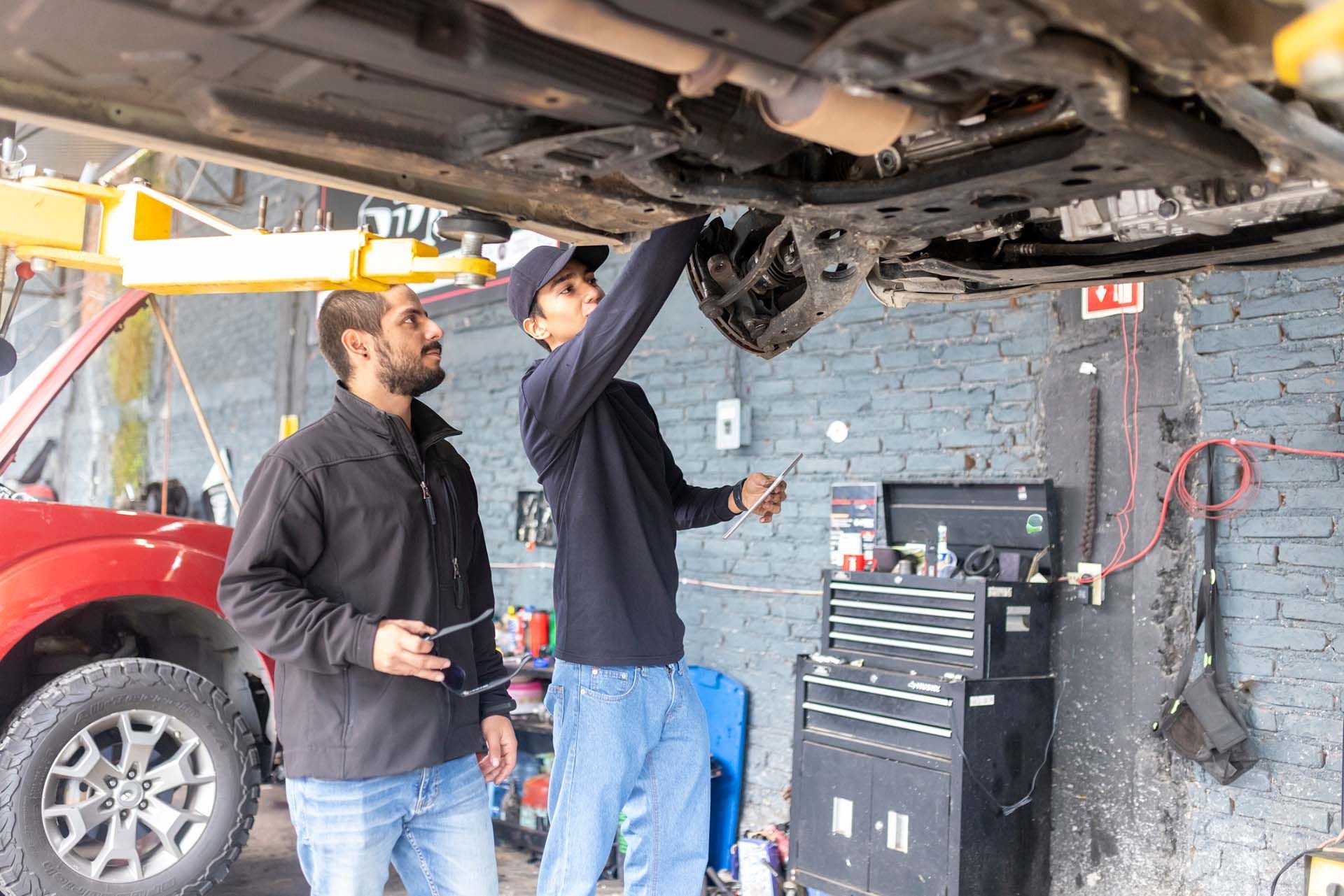 Two mechanics looking at the undercarriage of a car. Two mechanics looking at the undercarriage of a car.