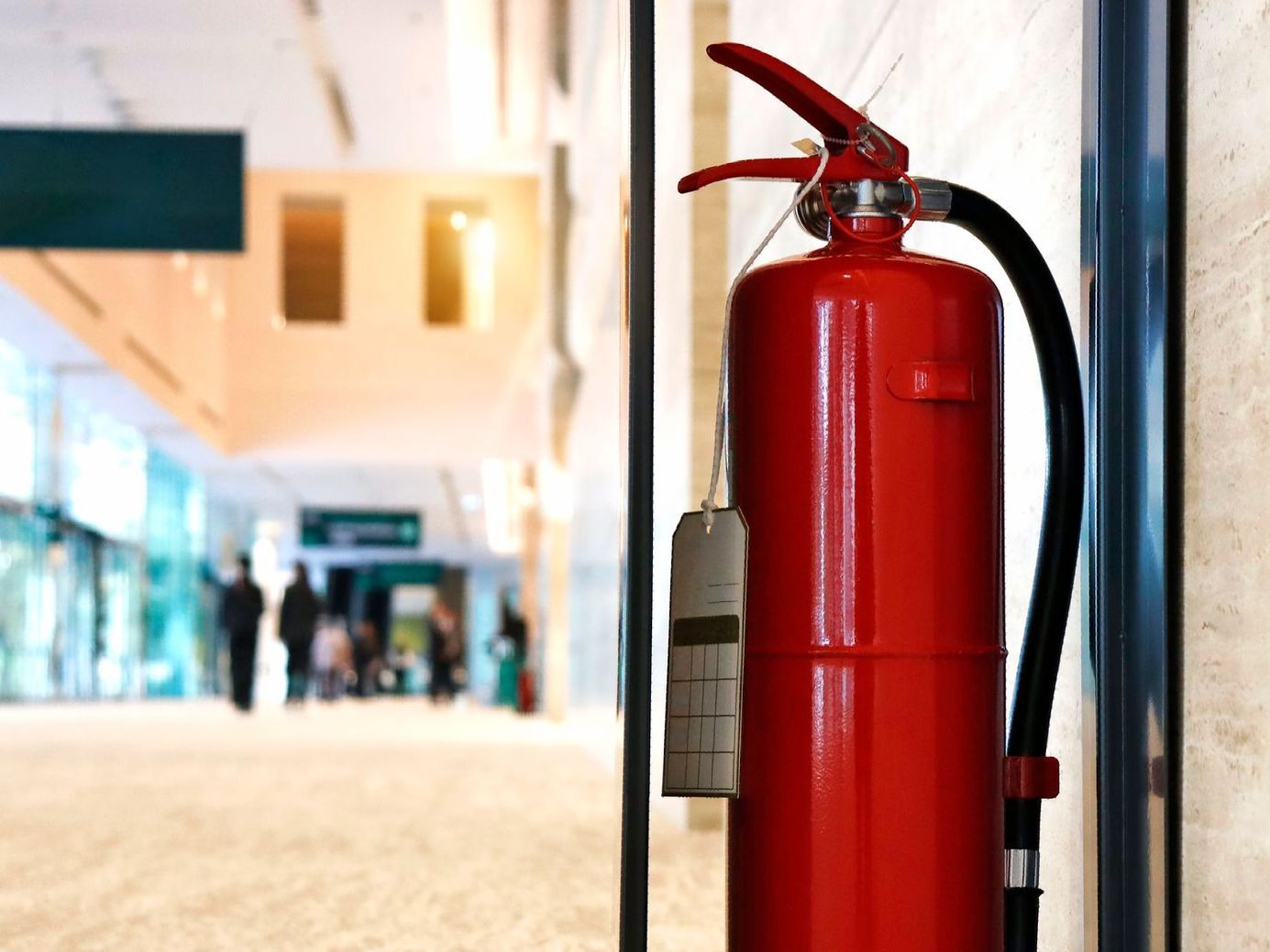 Un estintore rosso è seduto davanti a una porta a vetri.