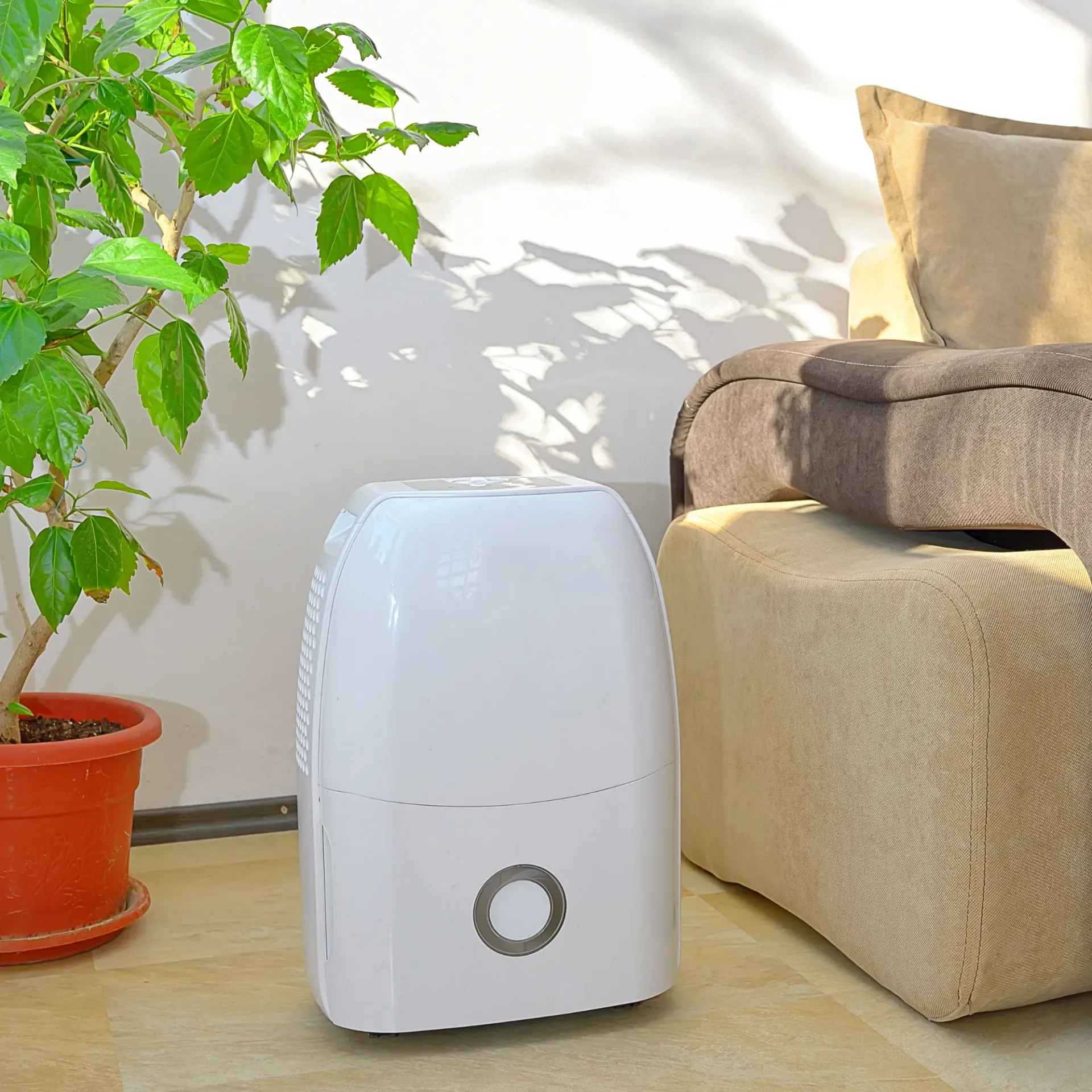 Kingdom Air LLC - A white air purifier is sitting in a living room next to a couch and a potted plant.