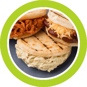 Arepas, filled with chicken, shredded meat, and sausage, stacked on a plate, with a green outline.