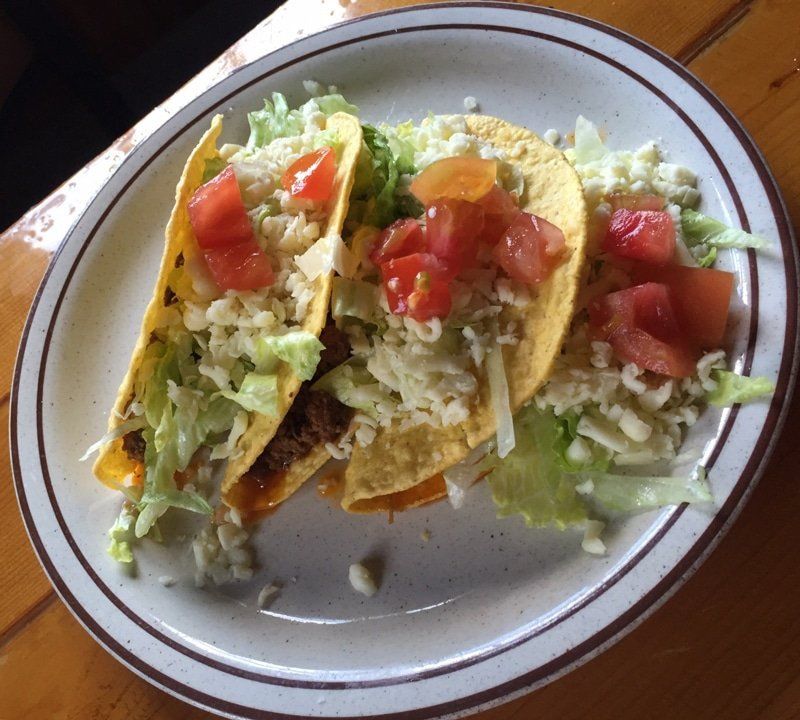A person is eating a plate of nachos with guacamole and cheese.