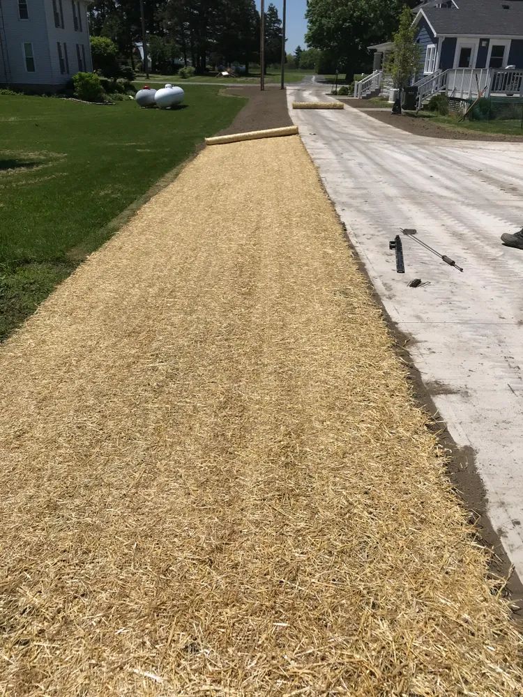 There is a lot of hay on the side of the road.