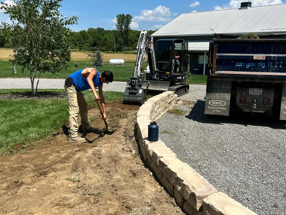A woman is digging in the dirt next to a dump truck.