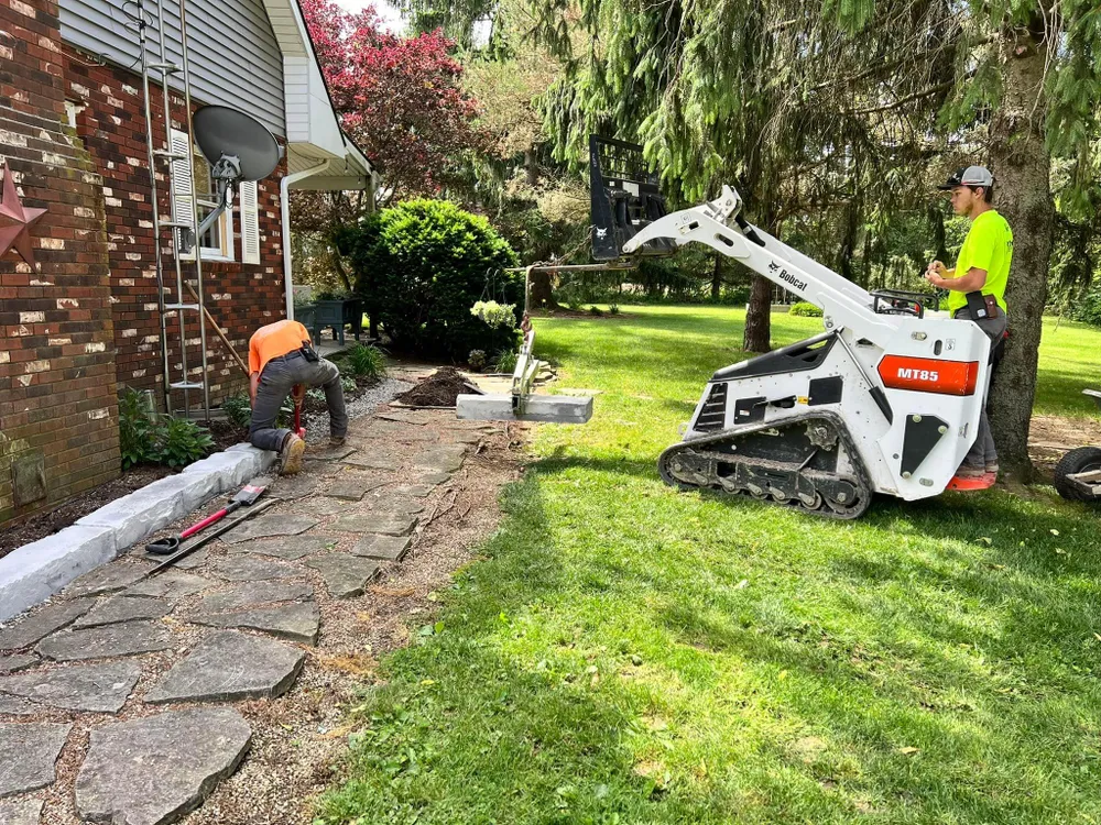 A couple of men are working on a walkway in front of a house.
