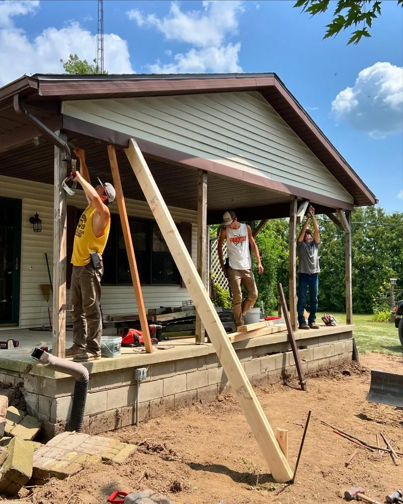 A group of people are working on a porch of a house.