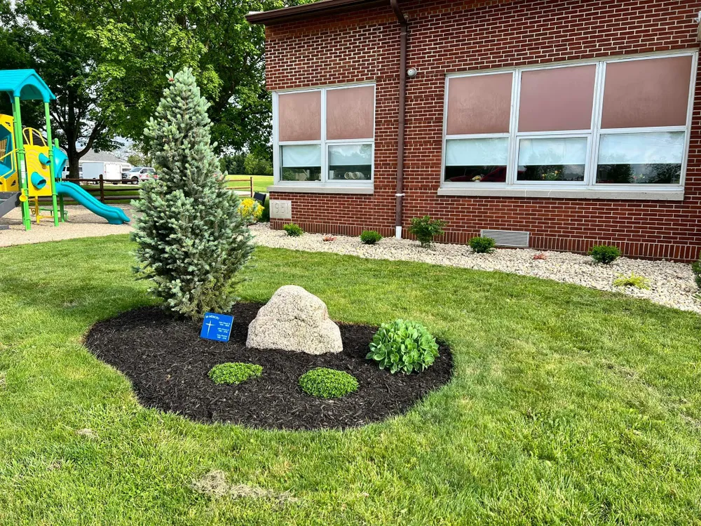 A lush green lawn in front of a brick building with a playground in the background.