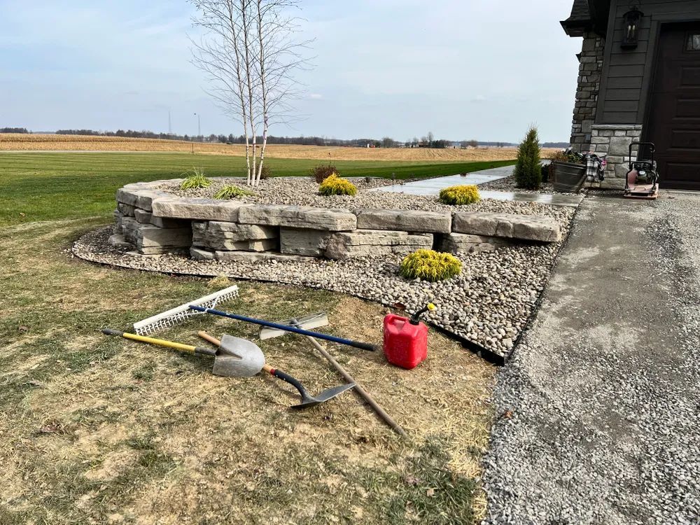 A bunch of gardening tools are laying on the ground in front of a house.