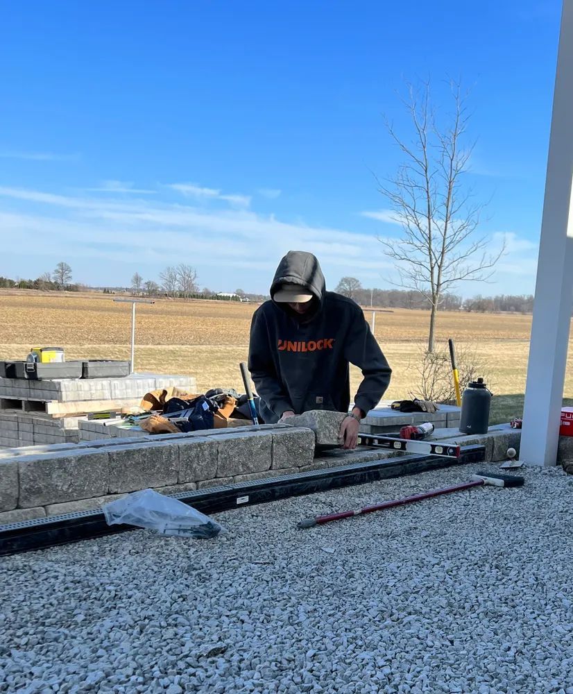 A man in a hoodie is working on a fence.