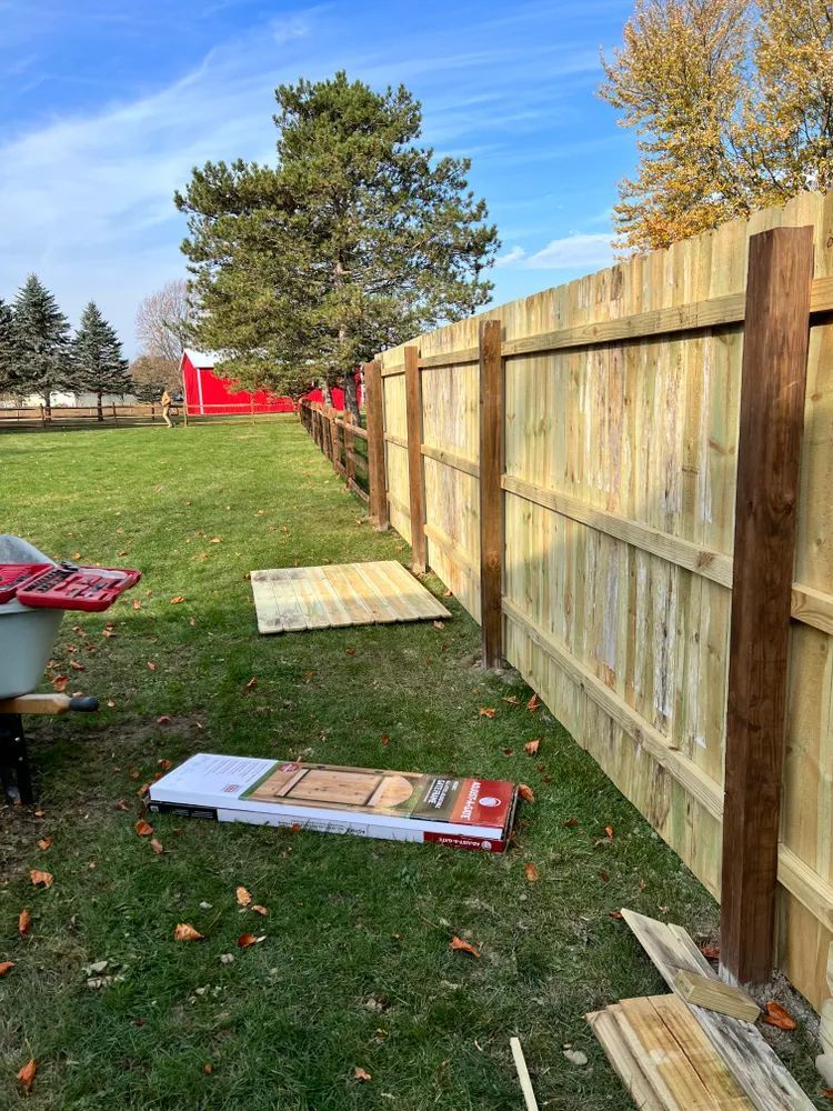 A wooden fence is being built in a backyard.