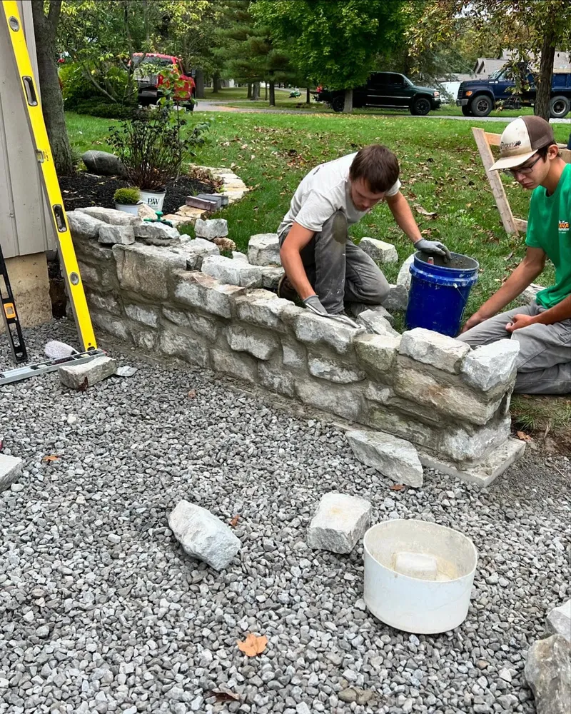 Two men are working on a stone wall.