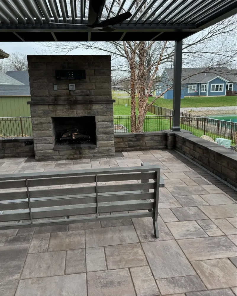 A patio with a fireplace and a bench under a canopy.