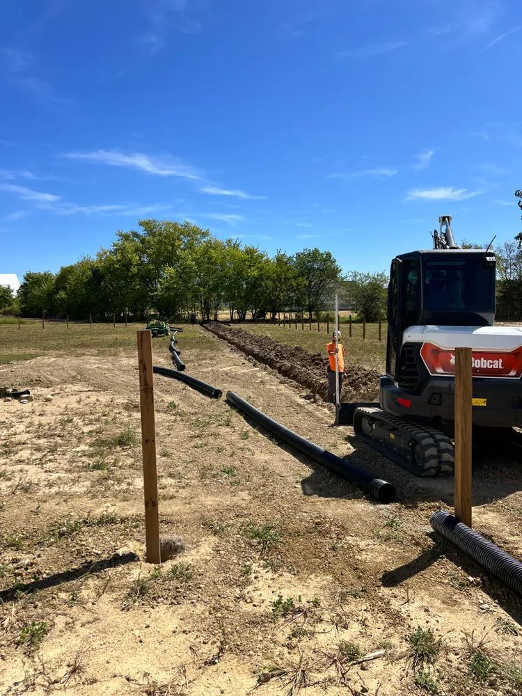 A bulldozer is parked in a dirt field next to a wooden fence.