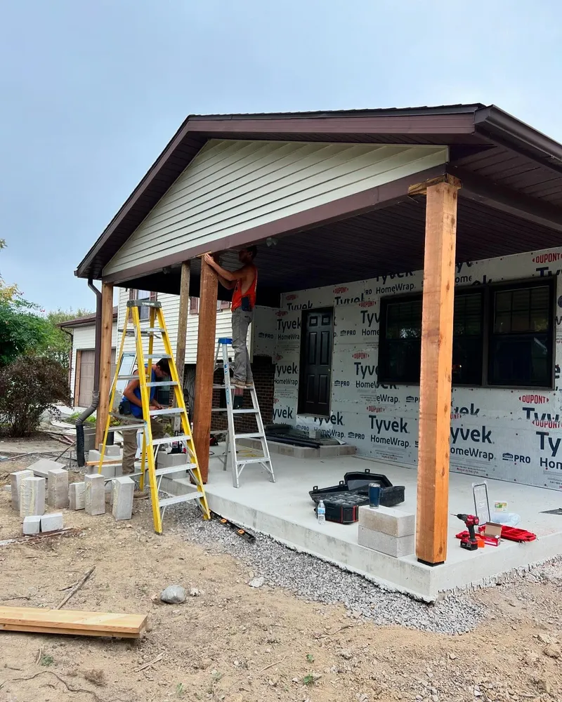 A man is standing on a ladder in front of a house under construction.