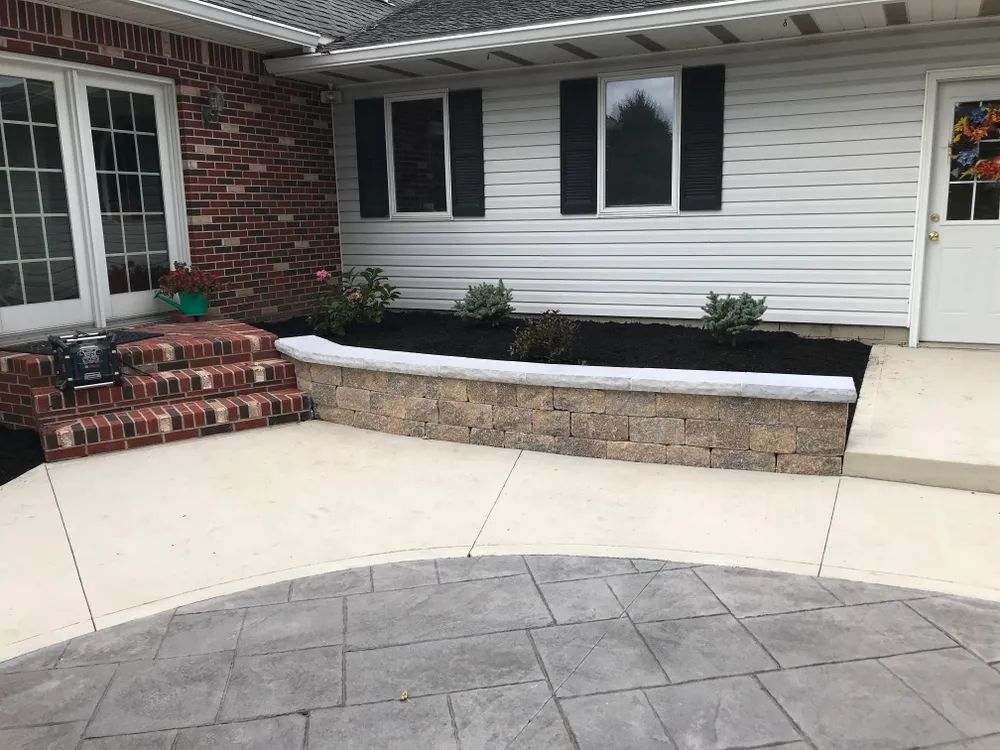 A brick house with a concrete walkway leading to the front door.