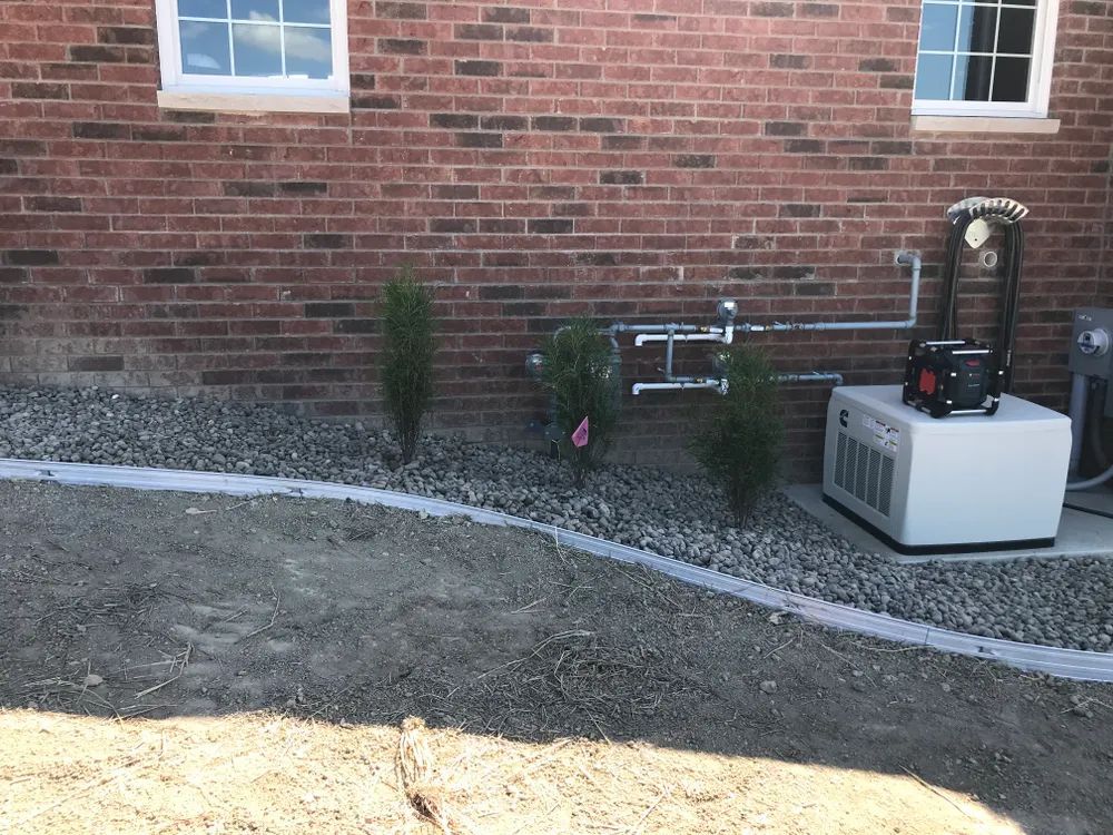 A generator is sitting in front of a brick building.