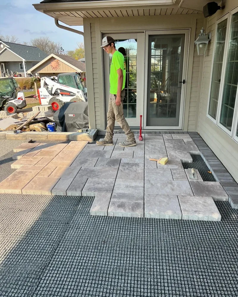 A man is standing on a patio in front of a house.