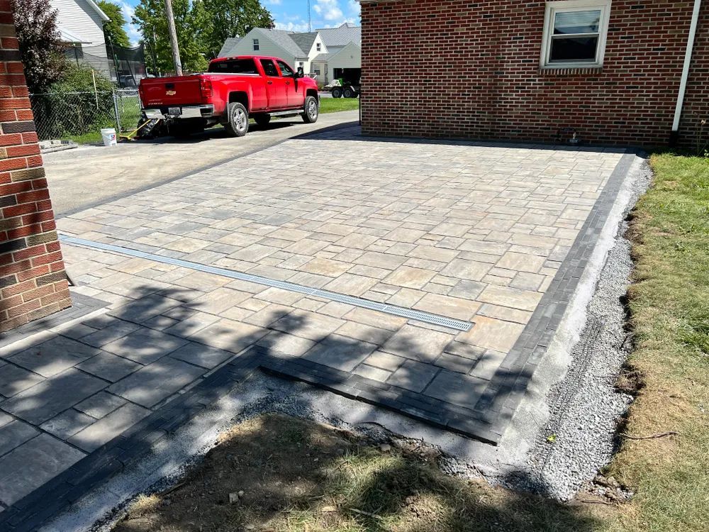 A red truck is parked in a driveway next to a brick house.