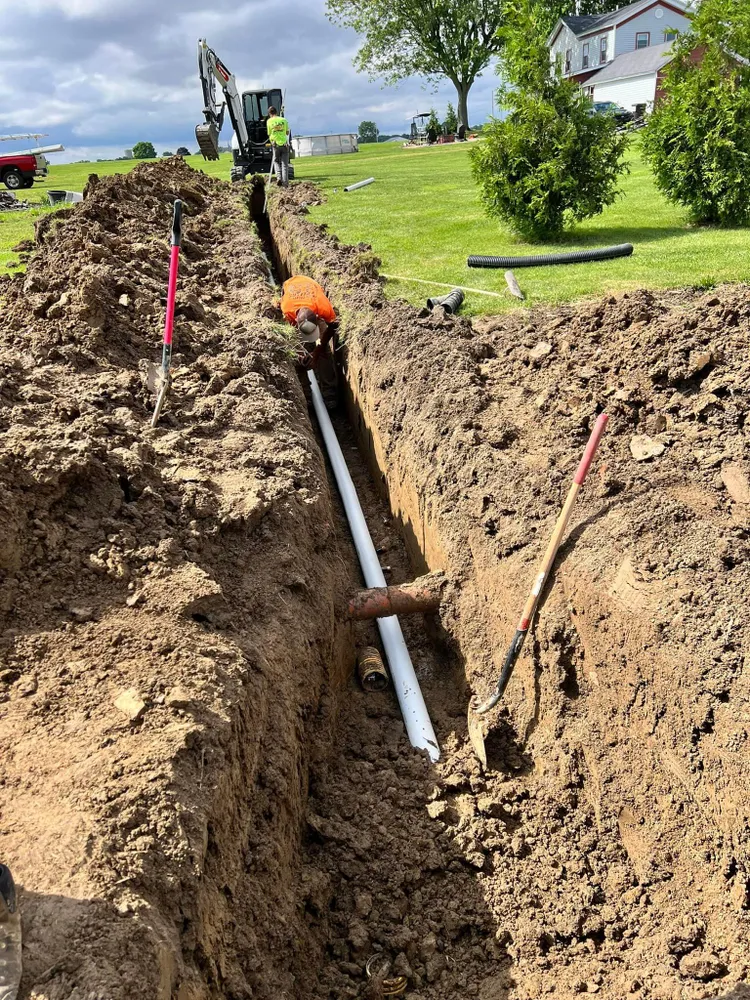 A man is digging a hole in the ground to install a pipe.