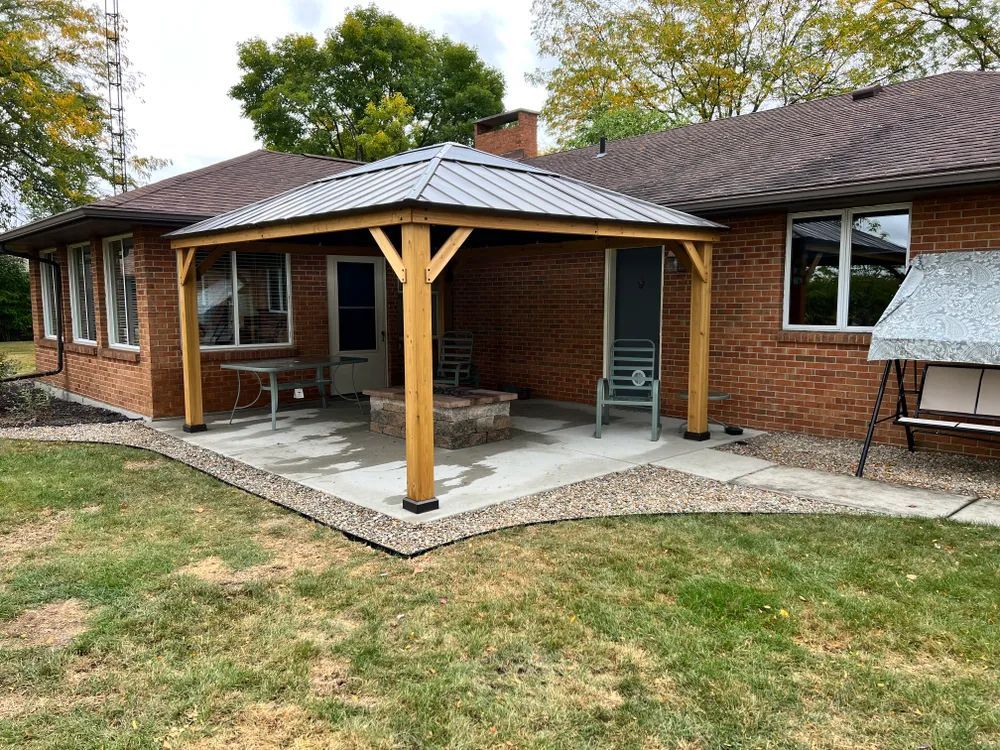 There is a gazebo in the backyard of a brick house.