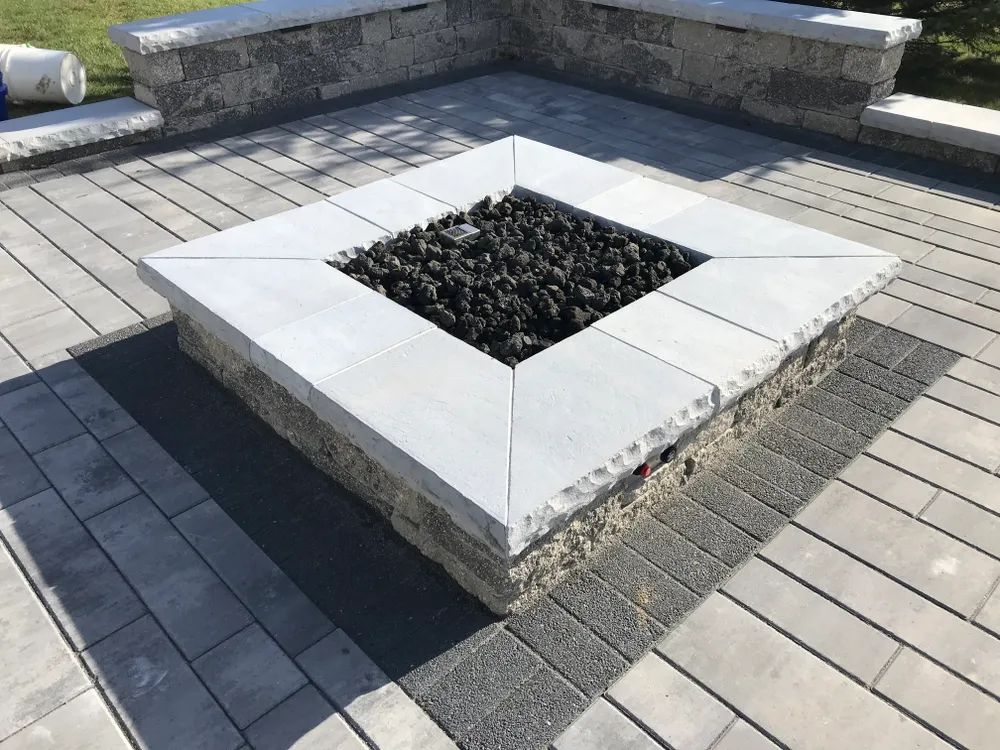 A fire pit is sitting on top of a brick patio.