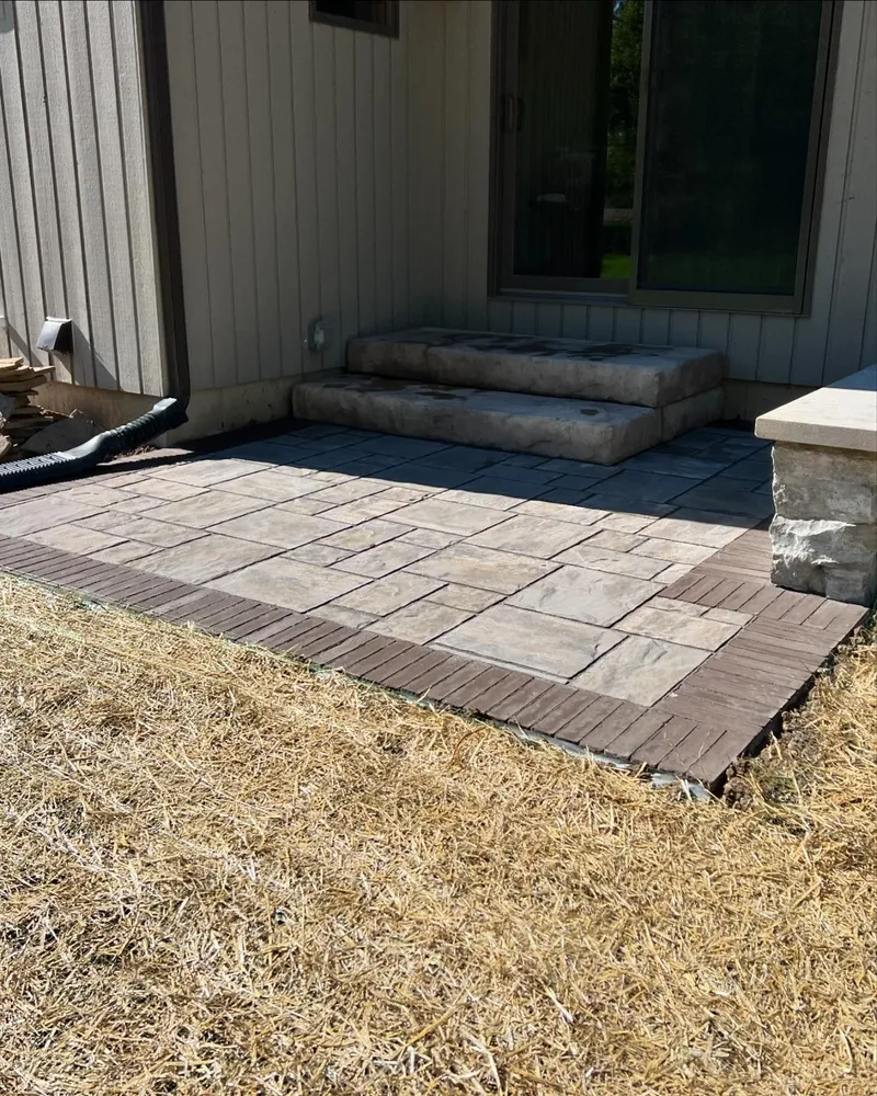 A patio with steps leading up to it is being built in front of a house.