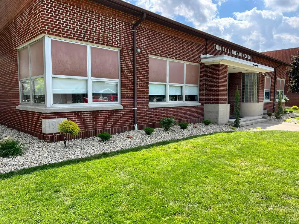 A brick building with a lot of windows and a lush green lawn in front of it.