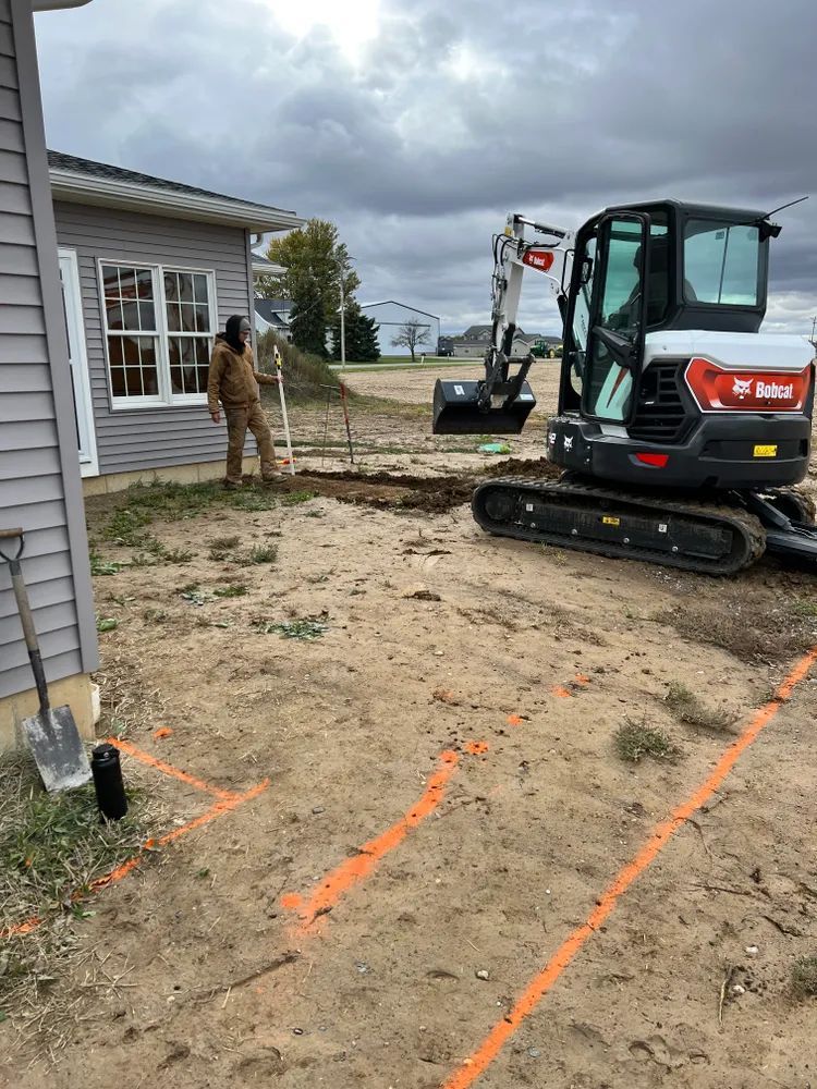 A man is standing next to a bulldozer in front of a house.