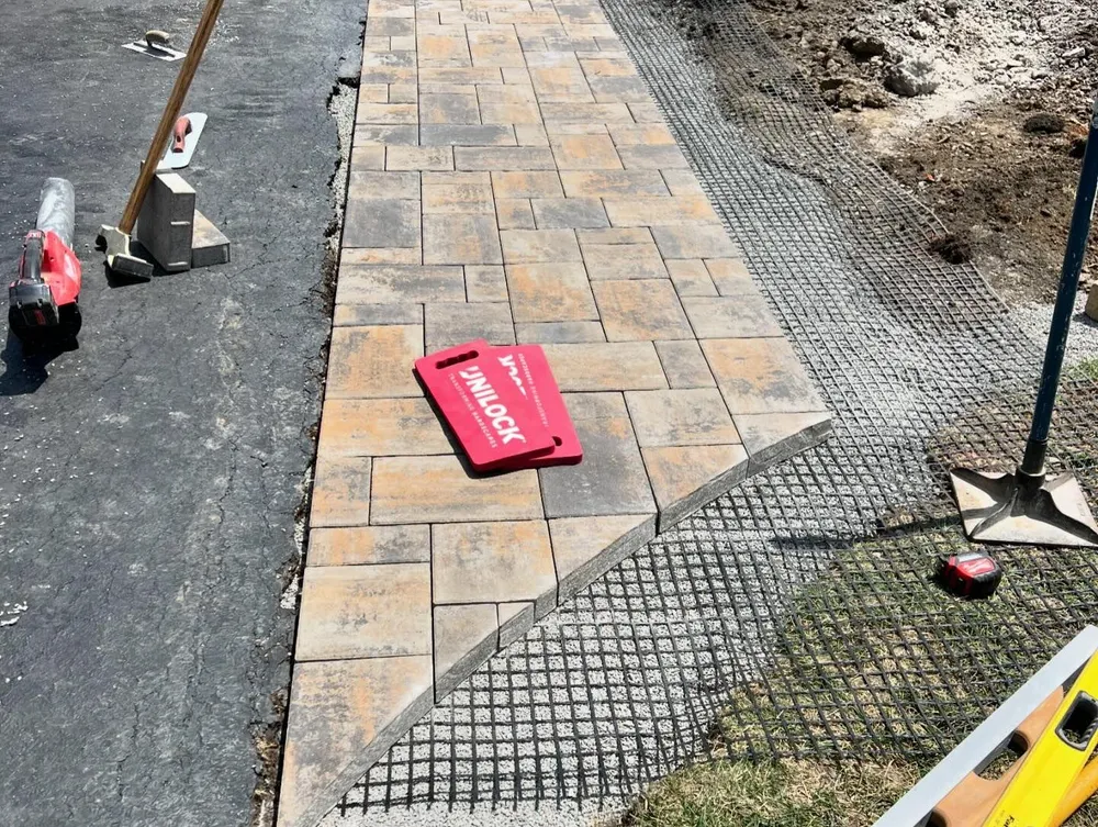 A walkway is being built with bricks and a red knee cushion
