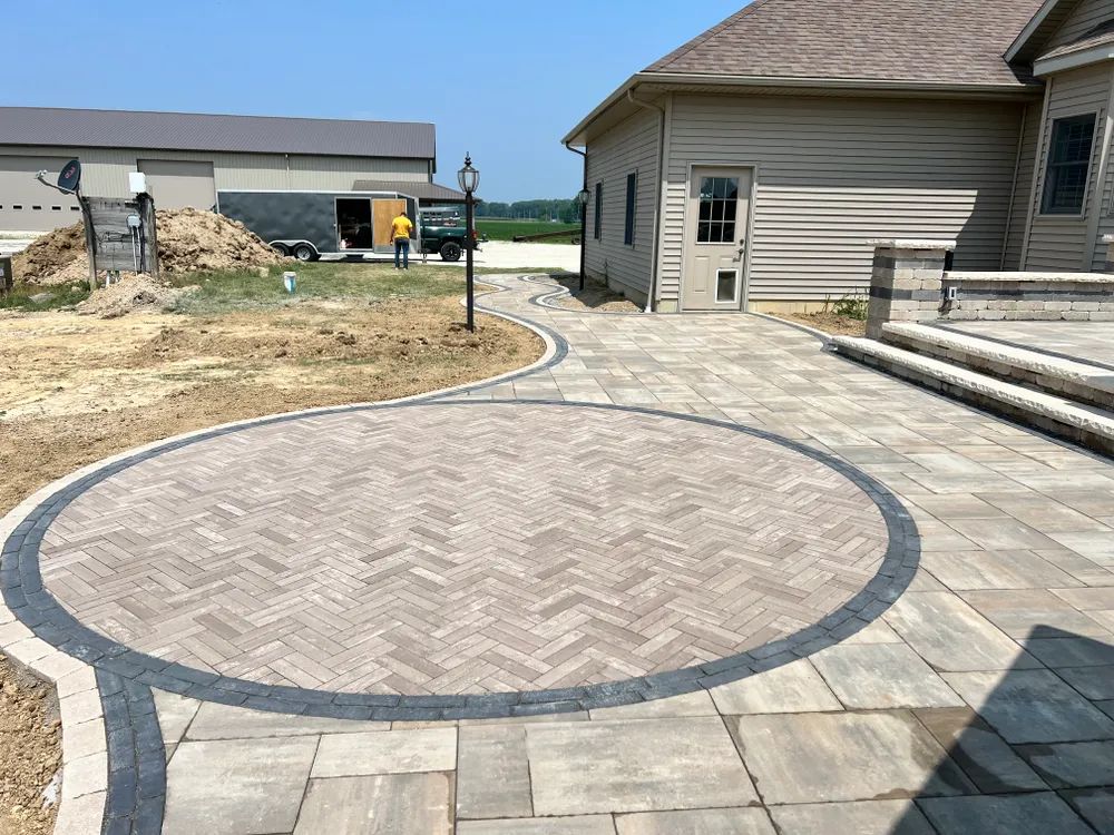 A patio with a circle in the middle of it and a house in the background.