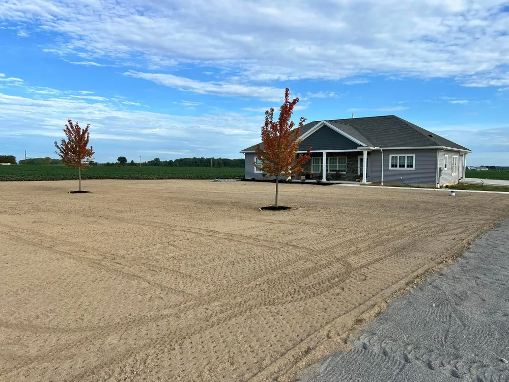 A house is sitting in the middle of a dirt field.