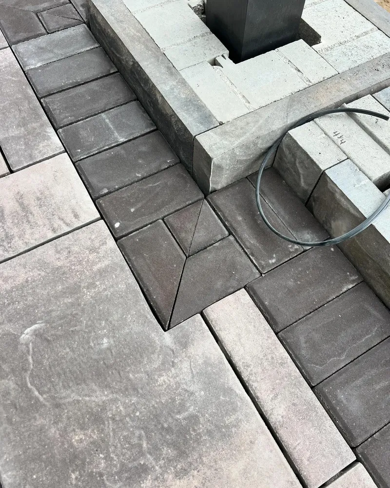 A close up of a brick walkway with a hose attached to it.