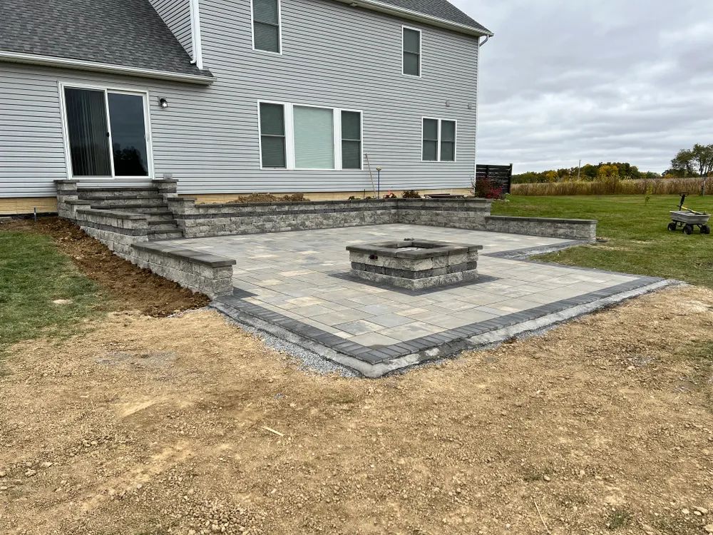 A patio with a fire pit and stairs in front of a house.