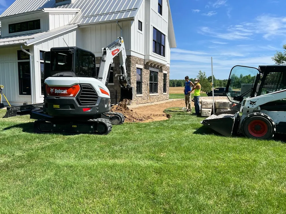 A bobcat excavator is parked in front of a house.