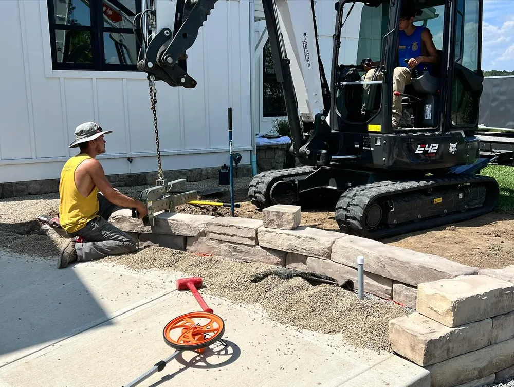 A man is sitting on the ground next to a bulldozer.