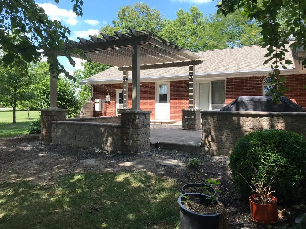 A brick house with a pergola and a patio in front of it.