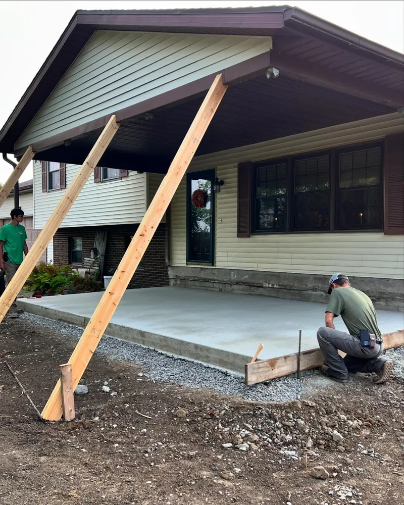 A man is kneeling in front of a house that is being built