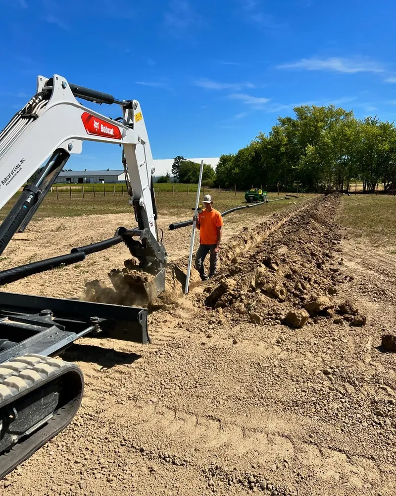 A man is standing in the dirt next to an excavator.