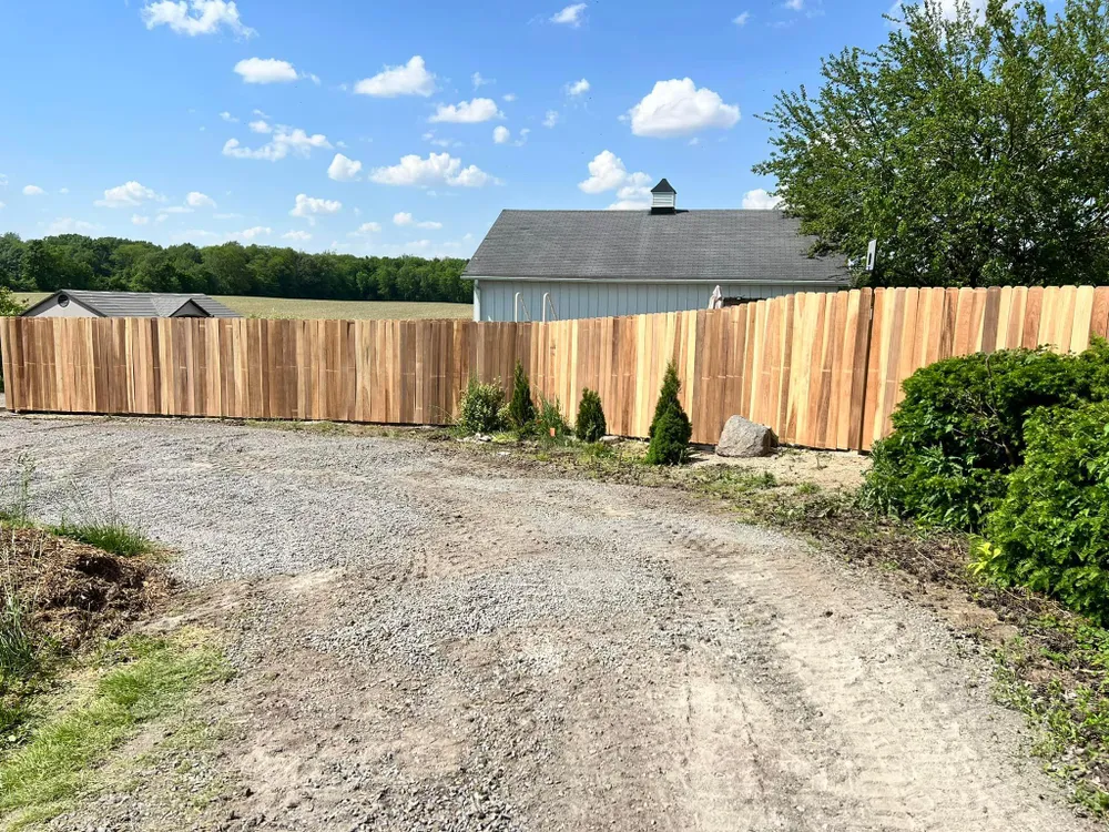 A wooden fence is along the side of a dirt road.