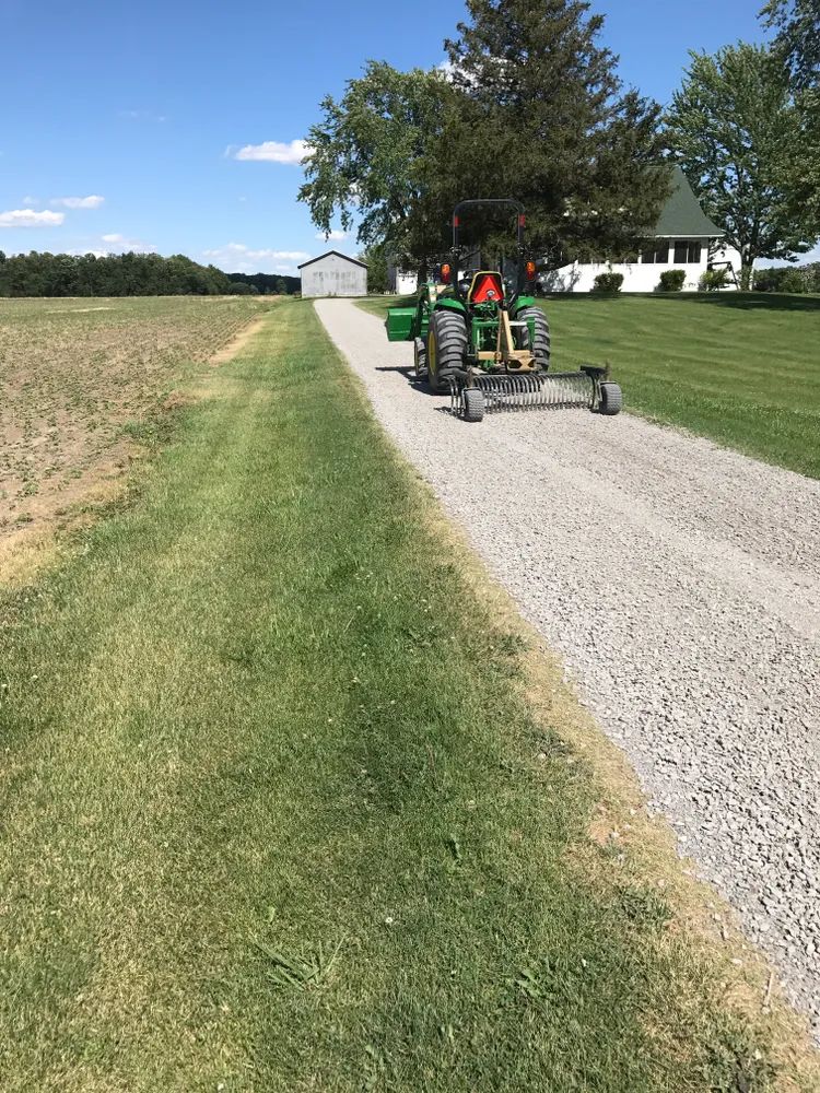 A green tractor is parked on the side of a dirt road.
