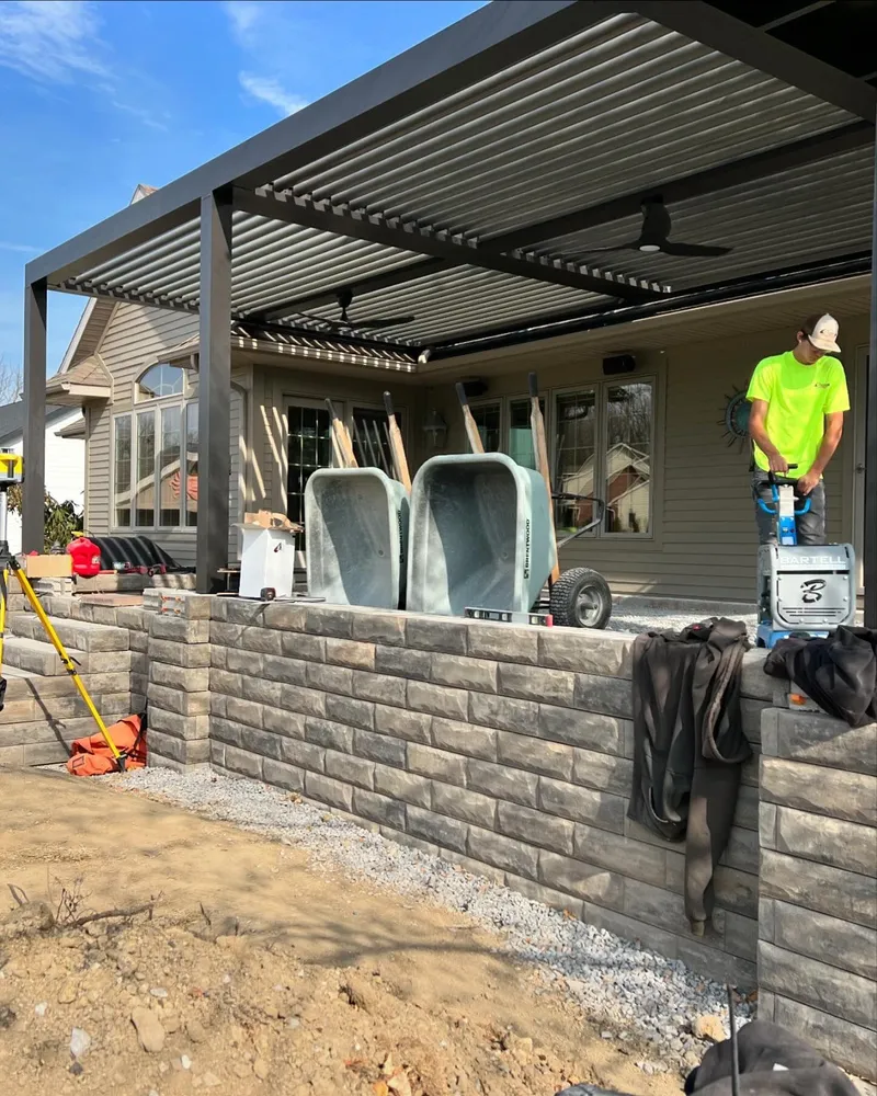 A man in a neon green shirt is standing in front of a house.