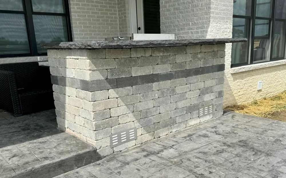 There is a brick wall with a counter top on it in front of a house.