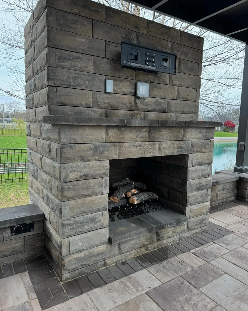 A brick fireplace with logs in it on a patio.