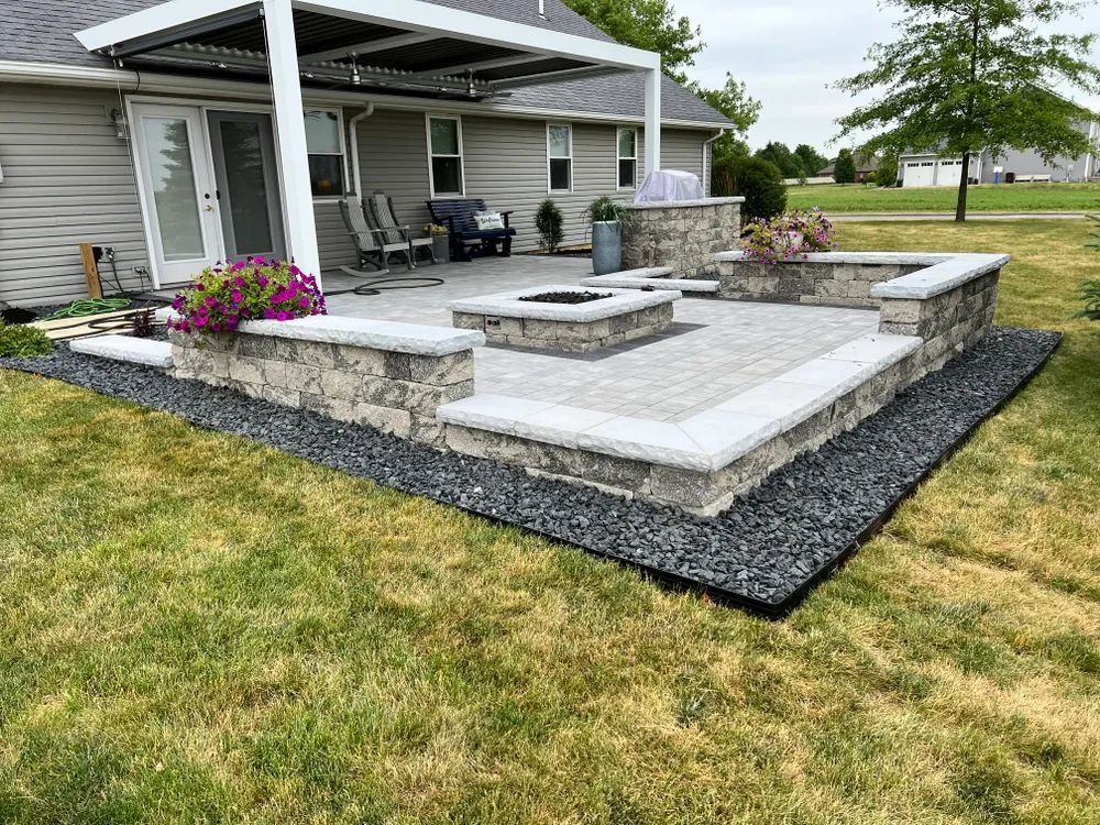 A patio with a fire pit and a covered porch in front of a house.