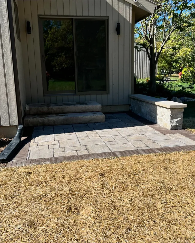 A patio with steps and a bench in front of a house.