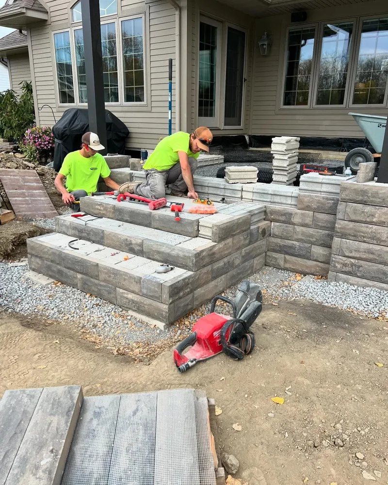 Two men are working on a staircase in front of a house.