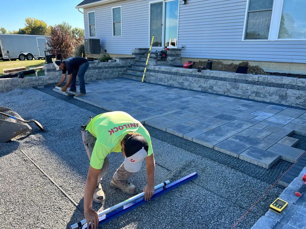A man is measuring a patio with a level in front of a house.