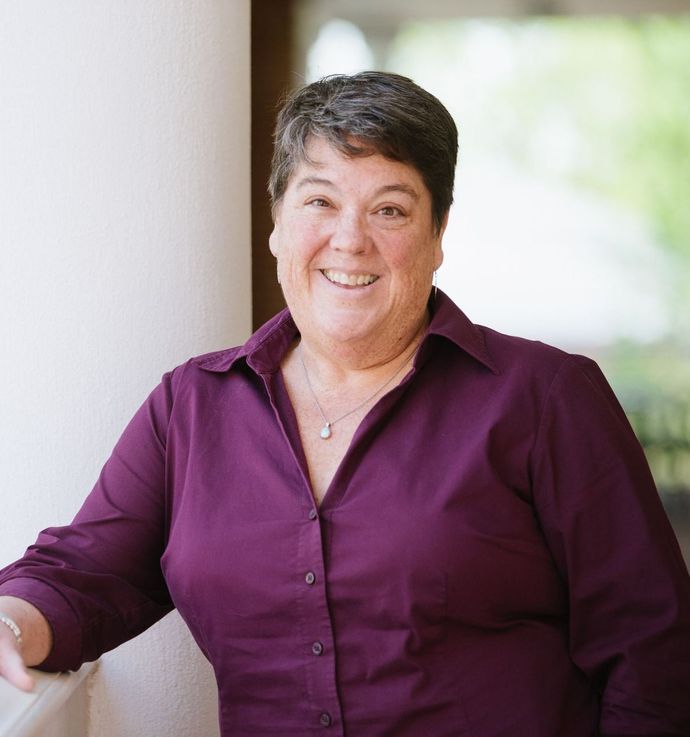 A woman in a purple shirt is smiling for the camera