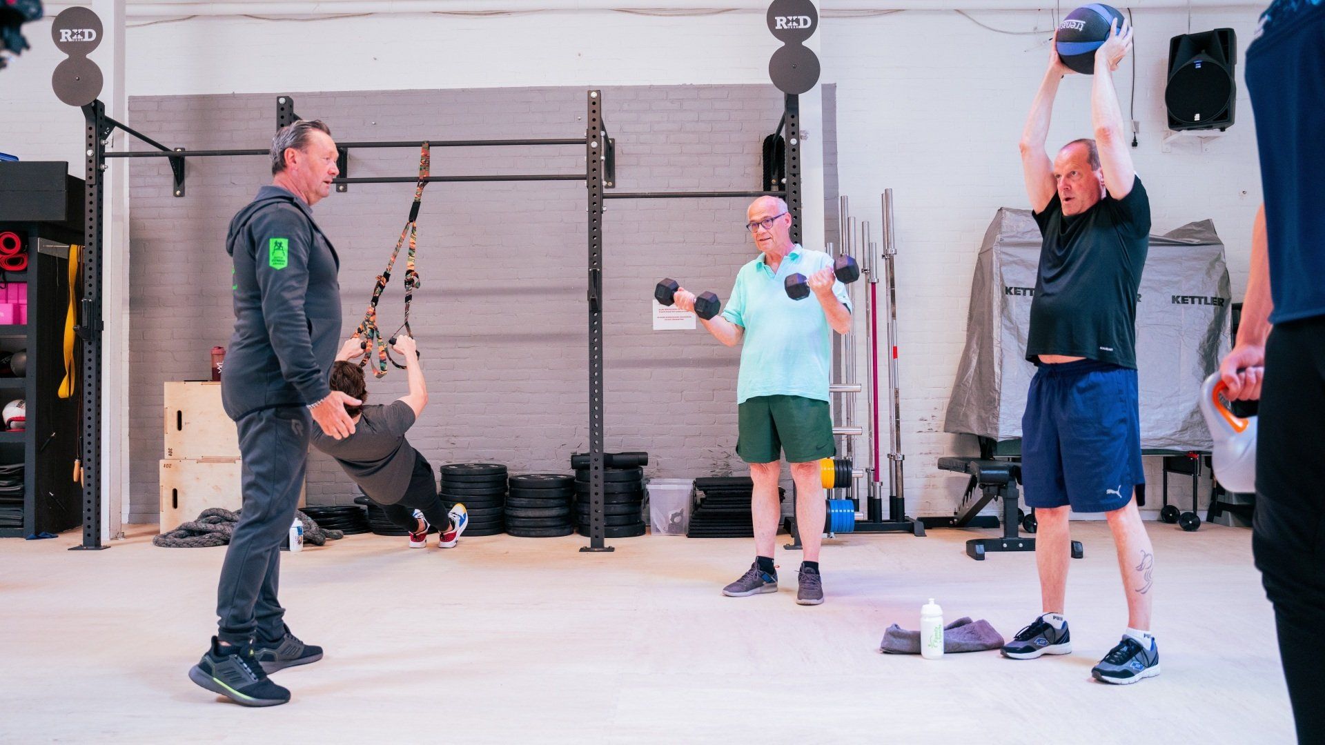 Een groep mannen doet oefeningen in een sportschool.