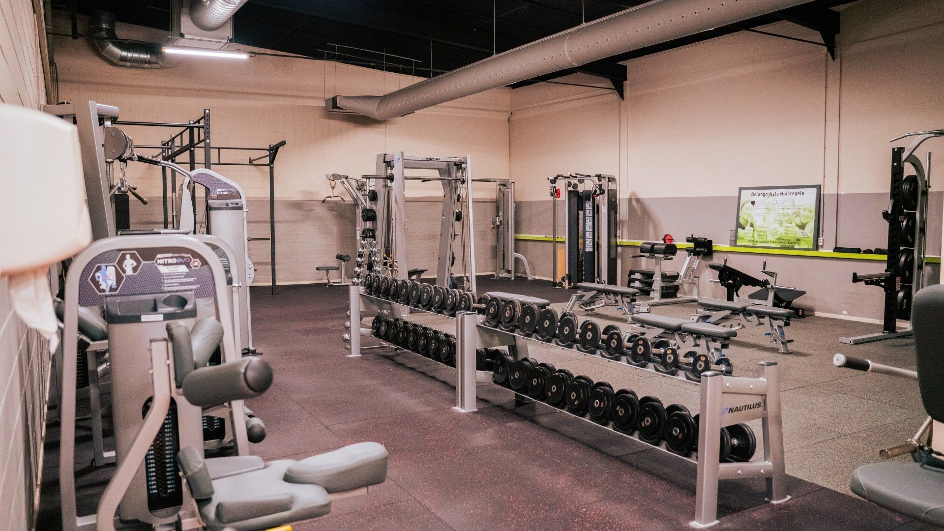 Een sportschool vol met veel fitnessapparatuur en dumbbells.