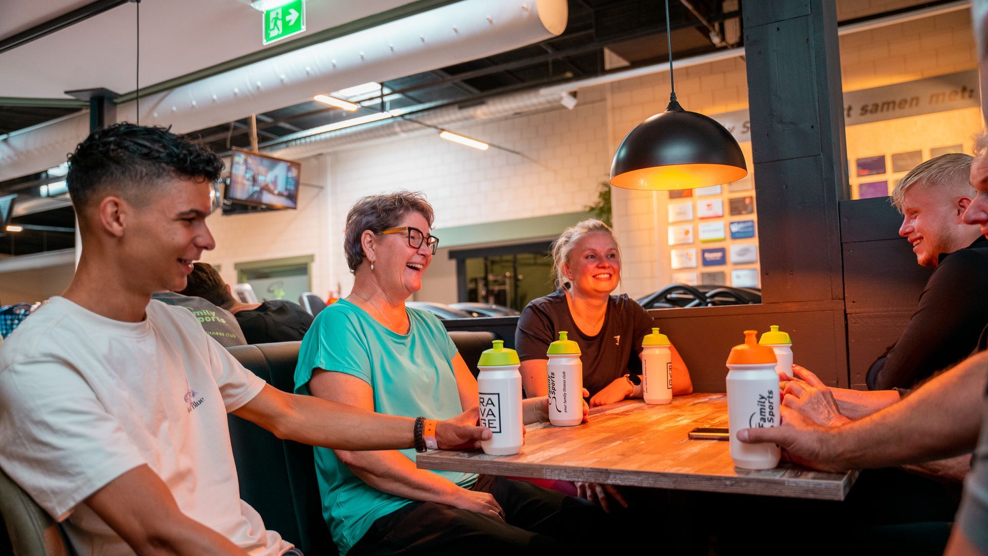 Een groep mensen zit aan een tafel met flessen water.